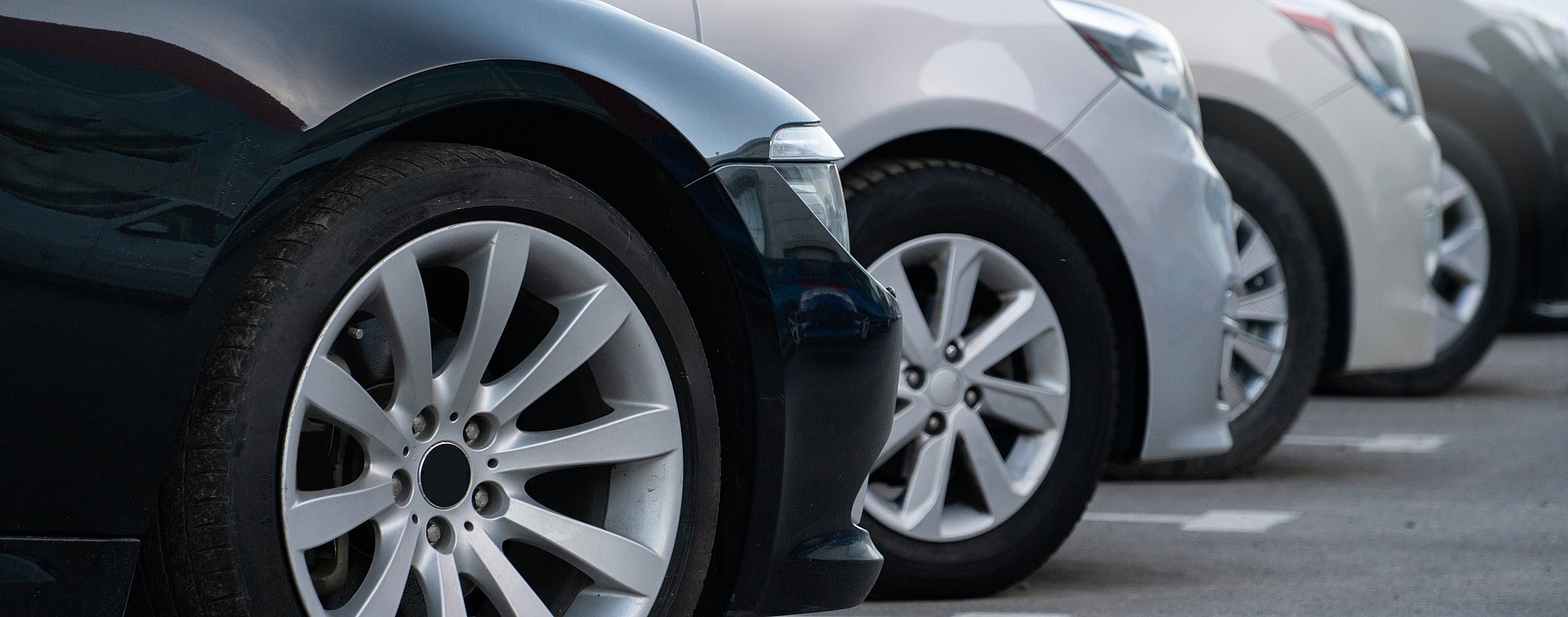 Grå bilar parkerade i rad på en parkeringsplats.